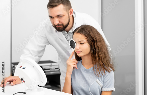 ophthalmologist doctor examines girl with diagnostics equipment in clinic