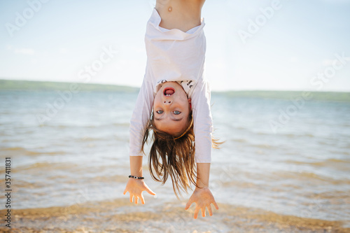Obraz na płótnie Little hiperemotional school age girl hanging upside down