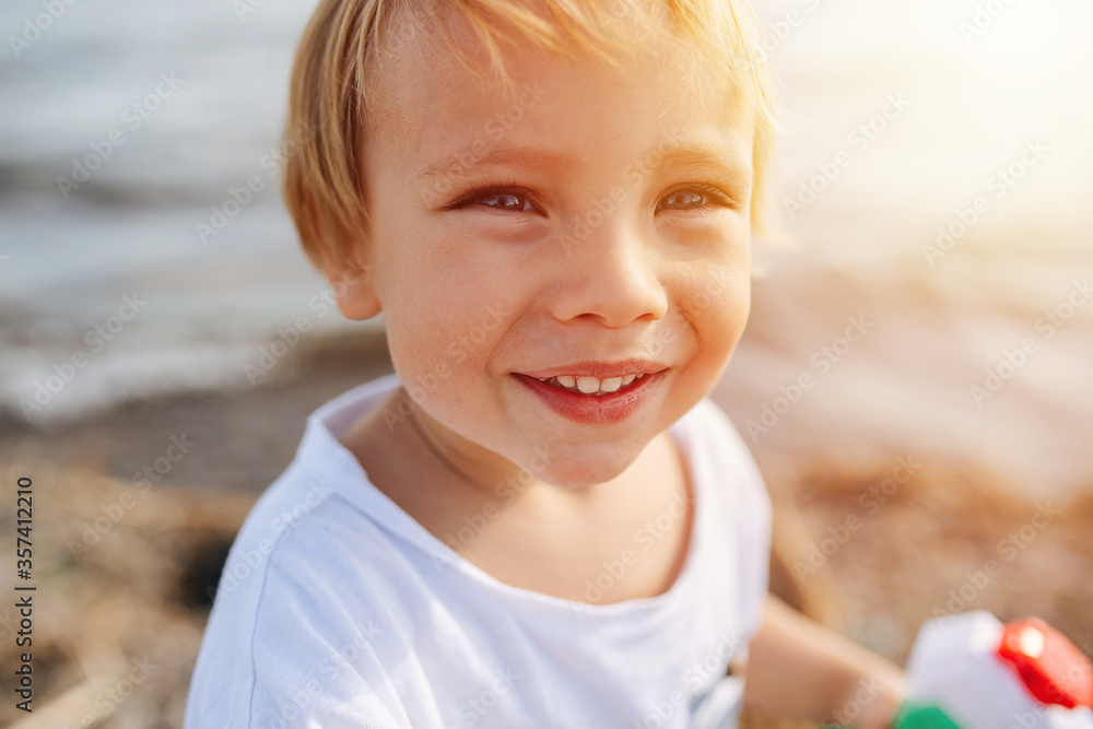 Portrait of a handsome little blond boy by the water under gentle sun Portrait of a handsome little blond boy by the water under gentle sun