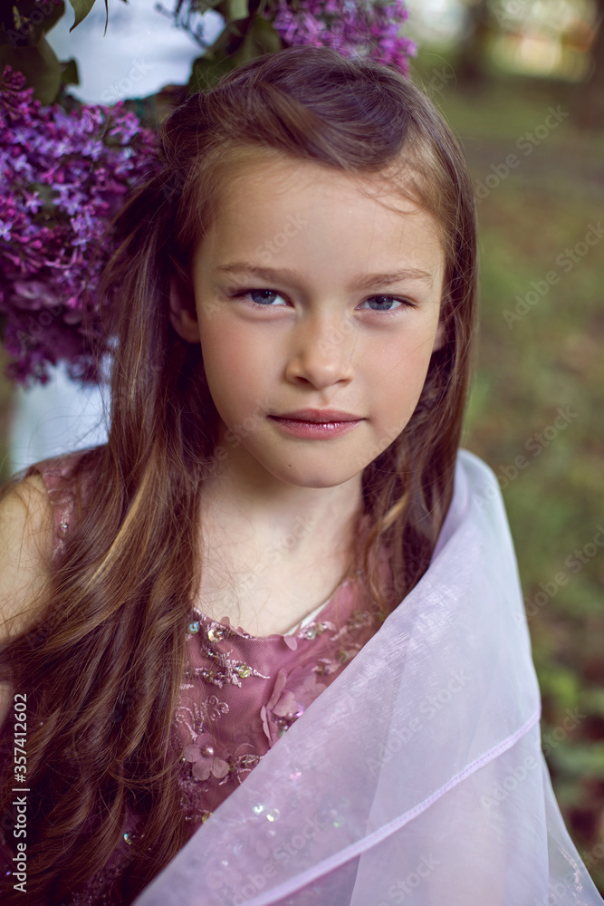 Caucasian girl child seven years old in a purple dress stands in nature Caucasian girl child seven years old in a purple dress stands in nature
