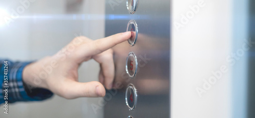 a close up hand pushing a button  in the lift elevator cabin photo