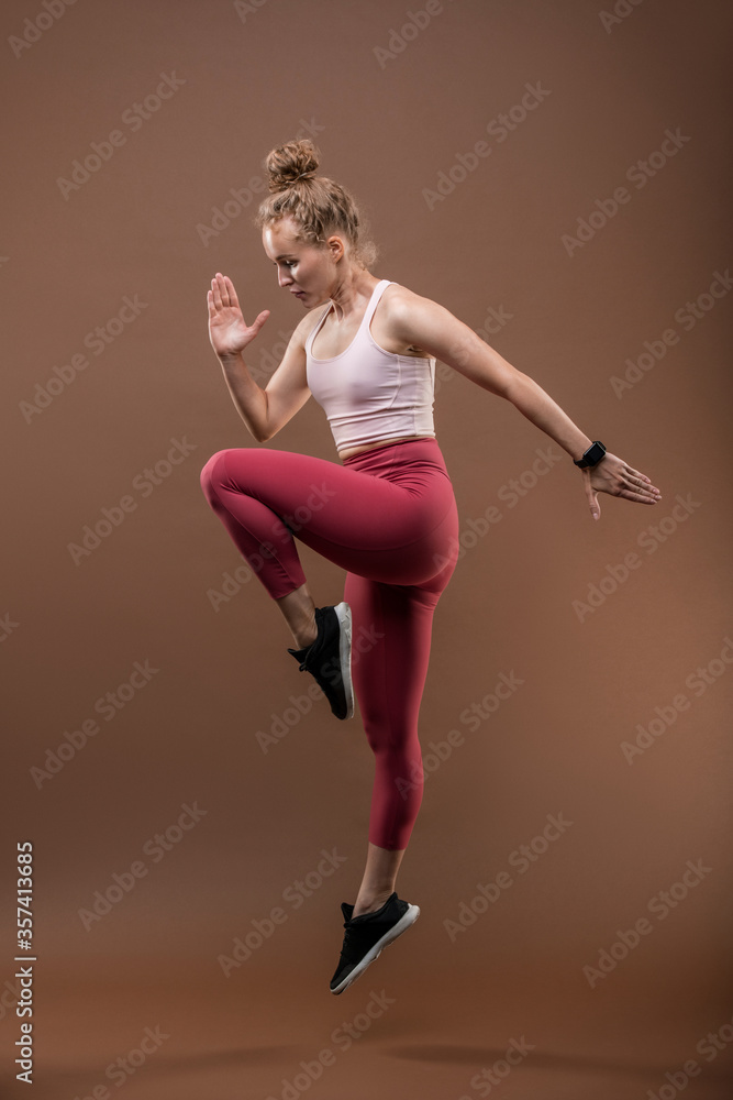 Fit female gymnast or performer in activewear dancing with one leg bent in knee