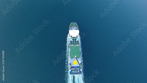 Top down drone shot of a ferry with yellow circle at the top dock sailing in the deep blue sea near Astakos, West Greece © Haris Photography