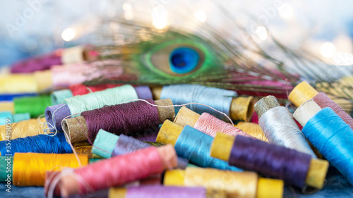 reels with multicolored threads of natural silk and peacock feather, close-up