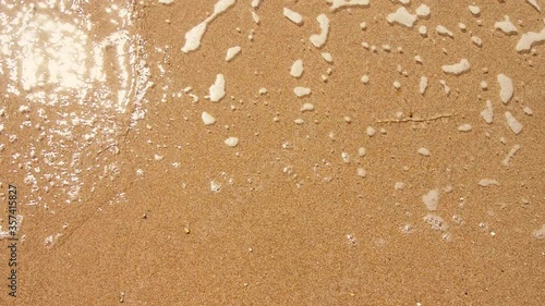 waves of clear sea water on yellow sand