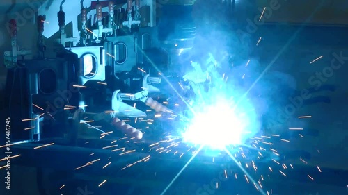 A welding robot performs welding work. A modern industrial robot welding machine is active in a factory. Automation of welding and mechanical procedures in production.