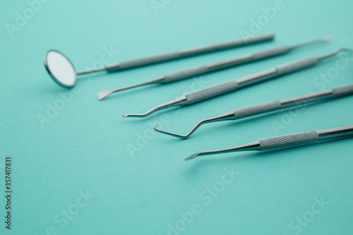 Professional Dentist tools in dental office: dentist mirror, forceps curved, explorer curved, dental explorer angular and explorer curved with chip, right. Dental Hygiene and Health conceptual image.