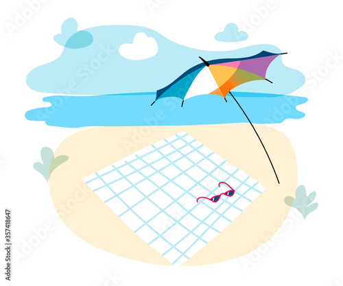 Sun shade umbrella and towel lie on sand. Beachfront landscape background