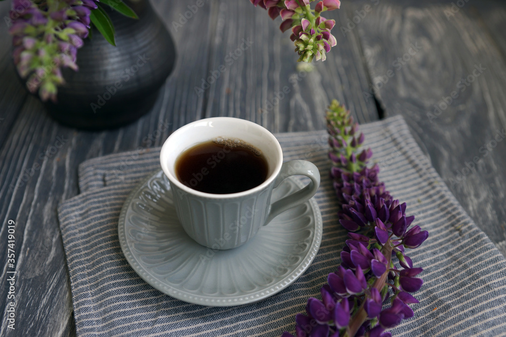Small mug with black coffee and lupins on a wooden table Small mug with black coffee and lupins on a wooden table