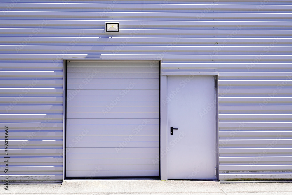 entrance roll-down shutters on gray building fire exit door in commercial industrial unit entrance roll-down shutters on gray building fire exit door in commercial industrial unit