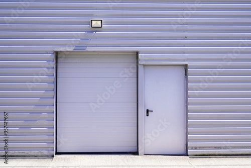 entrance roll-down shutters on gray building fire exit door in commercial industrial unit