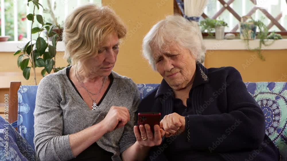 Patient daughter explains to her old mother how to use smartphone Patient daughter explains to her old mother how to use smartphone