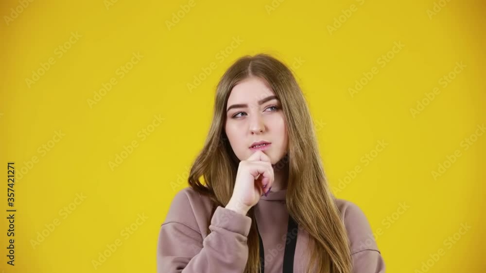Pensive young girl thinking on a yellow background, with copy space. Need to think it over. Concept bright backgrounds for advertising. Pensive young girl thinking on a yellow background, with copy space. Need to think it over. Concept bright backgrounds for advertising.