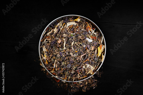 Colored Italian herbs Spices in a bowl, top view on a dark background, for delicious cooking