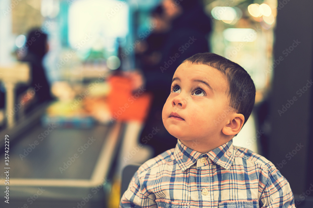 The little boy on a background of cash in a supermarket. toned