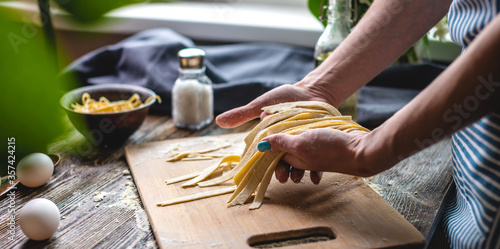 Woman is carefully holding raw homemade noodles in her hands. Process of cooking handmade pasta in a cozy atmosphere photo