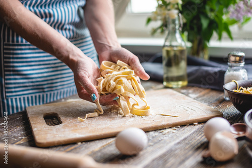 Woman is carefully holding raw homemade noodles in her hands. Process of cooking handmade pasta in a cozy atmosphere