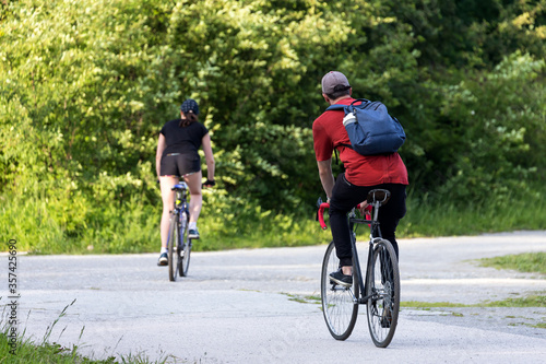 Fototapeta Naklejka Na Ścianę i Meble -  Two cyclist riders on an asphalt track on a warm summer day, rear view