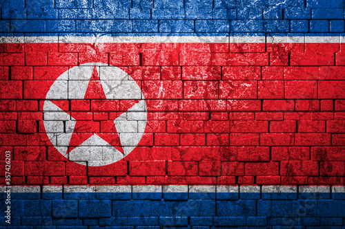 National flag of North Korea on brick wall background.The concept of national pride and symbol of the country. Flag banner on stone texture background.