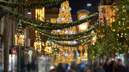 Unrecognizable people walk down the street with Christmas and New Year decoration. Bright Christmas street illumination. European city decorated for the Christmas Holiday. UHD, 4K