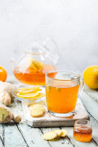 Ginger tea in a glass cup with lemon and mint on light background