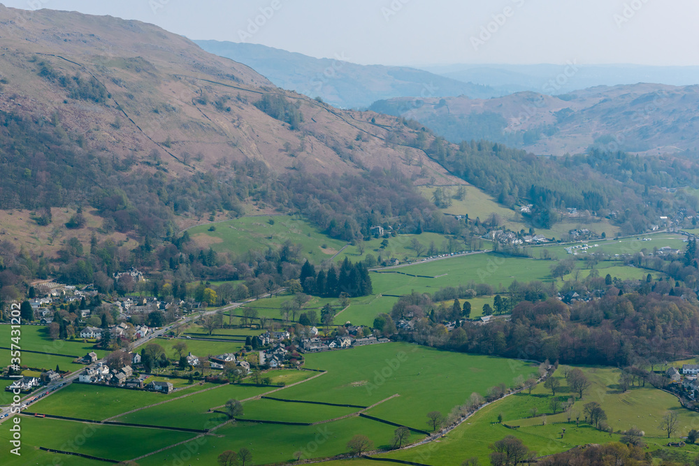 Grasmere village, Fairfield horseshoe and Loughrigg Fell in the background, seen from the summit of Helm Crag, Grasmere, Lake District, Cumbria, UK