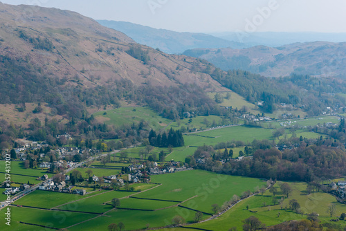 Grasmere village, Fairfield horseshoe and Loughrigg Fell in the background, seen from the summit of Helm Crag, Grasmere, Lake District, Cumbria, UK