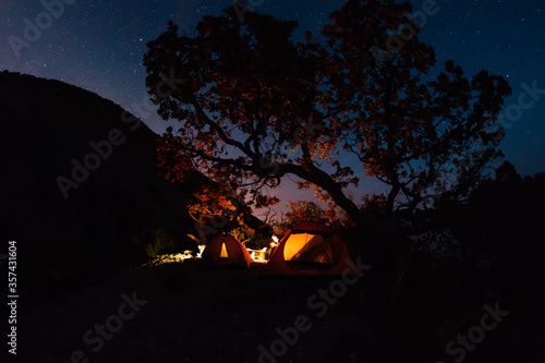 Night star sky and travelers with bonfire and tent