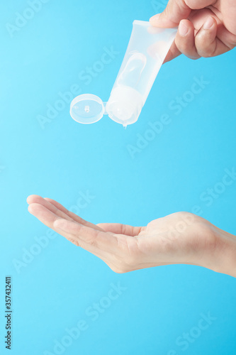 Close up woman hands using wash hand sanitizer gel in blue background.
