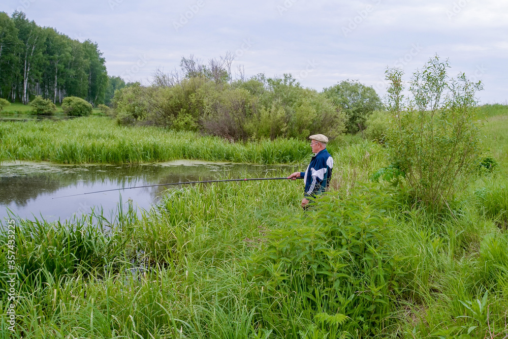 an elderly fisherman is fishing in a small river an elderly fisherman is fishing in a small river