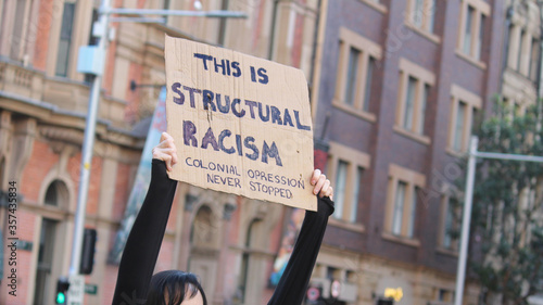 Sydney, NSW / Australia - June 6 2020: Black Lives Matter March. Protesting Aboriginal rights  death of. Sign reading 'This is structural racism, colonial oppression never stopped'.