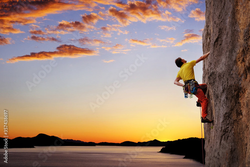 A silhouette of man climbing on rock, mountain  climber at sunset.
