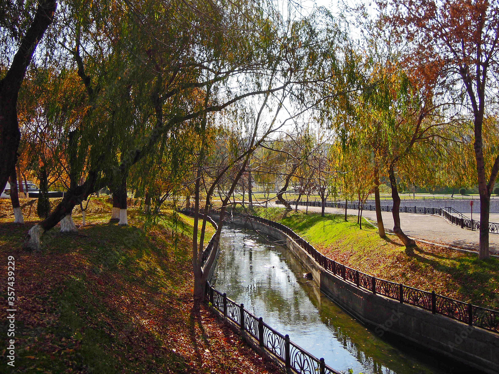Autumn view in central Tashkent park of Mirzo Ulugh Beg on colorful trees, river channel and fallen leaves. Picture taken in Tashkent, Uzbekistan Autumn view in central Tashkent park of Mirzo Ulugh Beg on colorful trees, river channel and fallen leaves. Picture taken in Tashkent, Uzbekistan