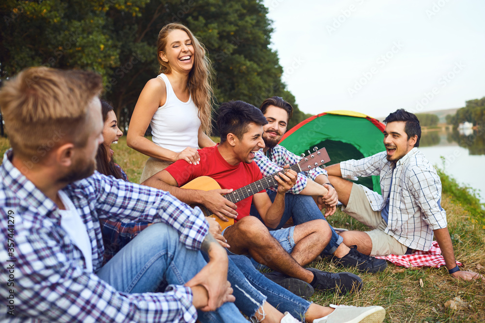 Friends with a guitar on a picnic on nature in autumn.