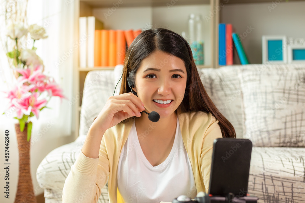 Young businesswoman or operator woman working at home during her country get pandemic disease, coronavirus, covid19. Asian woman use headphone speaker. Girl get new normal life, social distancing Young businesswoman or operator woman working at home during her country get pandemic disease, coronavirus, covid19. Asian woman use headphone speaker. Girl get new normal life, social distancing