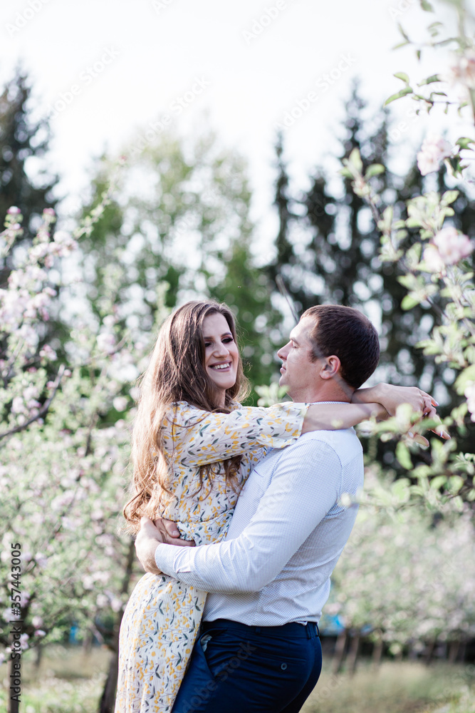 lovely loving couple walking in a freshly blooming apple orchard, spending time together outdoors lovely loving couple walking in a freshly blooming apple orchard, spending time together outdoors