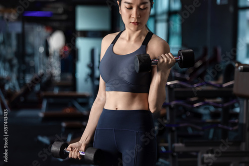 young Athletic woman with muscular body exercising Crossfit. Asian Woman in sportswear doing a workout with the kettlebell at the gym