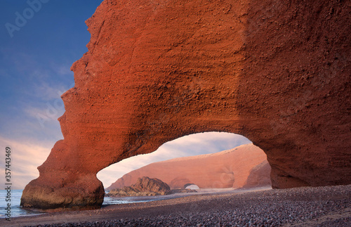 Famous Red arches at Legzira beach near Sidi Ifni on Atlantic coast on sunset in Morocco, North Africa. One of two rock archways has collapsed in 2016.