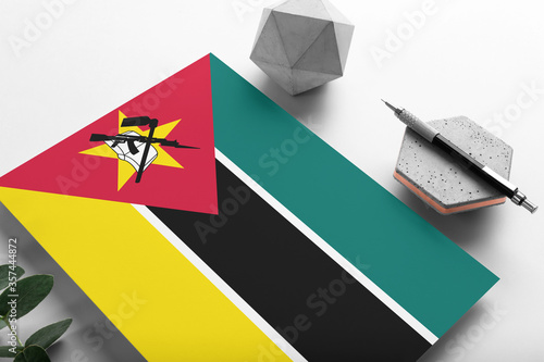Mozambique flag on minimalist paper background. National invitation letter with stylish pen on stone. Communication concept.