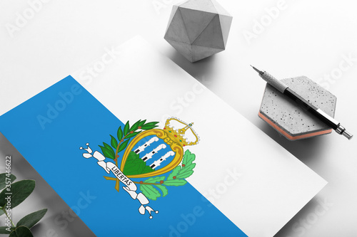 San Marino flag on minimalist paper background. National invitation letter with stylish pen on stone. Communication concept.