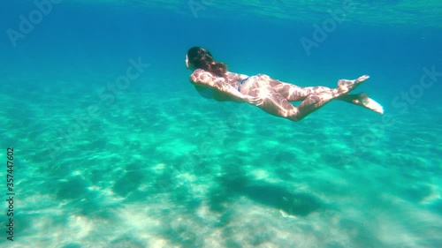 Young woman swimming underwater in the ocean alone at remote beach