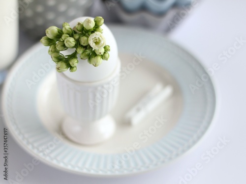 Breakfast. An eggshell vase with a bunch of white flowers stands on the table.