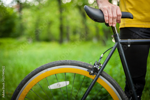 Cyclist with his bike, close up. Outdoor photography. you can see his hands and the wheel. © Evgeny Leontiev