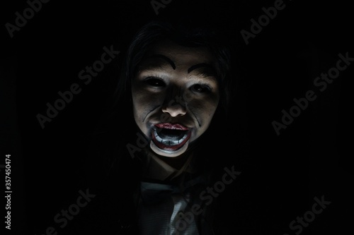 Obraz na plátně Scary possessed girl with a creepy doll makeup in a dark room - horror concept