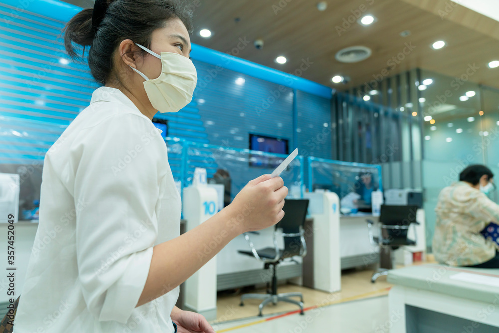 New normal asian female sit and write paper work at commercial bank with face mask and social distancing new lifestyle after covid 19 spread epidemic New normal asian female sit and write paper work at commercial bank with face mask and social distancing new lifestyle after covid 19 spread epidemic