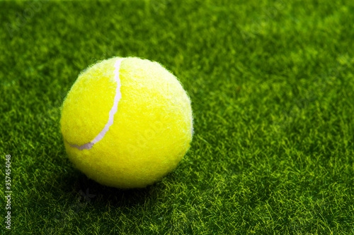 A tennis ball on a green artificial lawn with a copy of space. © Dmitry Smirnov