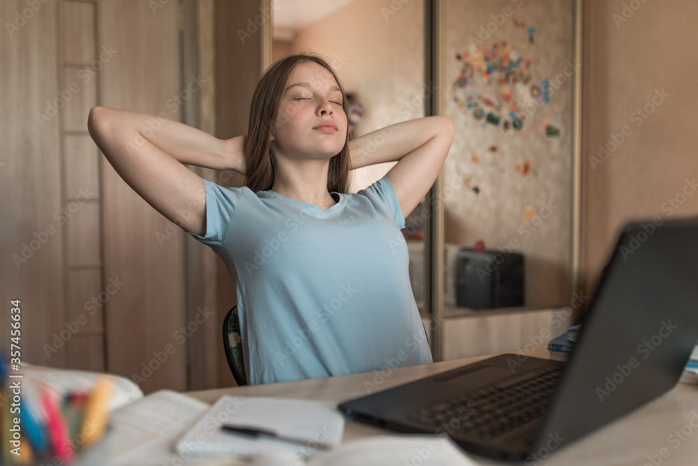 Teenager girl, resting stretching and relaxing, enjoying studying at home, electronic education at home using a laptop on the Internet. Successful exam and test. Emotions of pleasure and comfort. Teenager girl, resting stretching and relaxing, enjoying studying at home, electronic education at home using a laptop on the Internet. Successful exam and test. Emotions of pleasure and comfort.