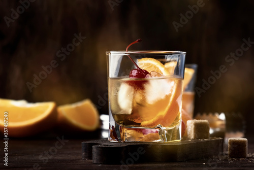 Foto Old fashioned cocktail with bourbon, cane sugar, orange slice, cherry and orange