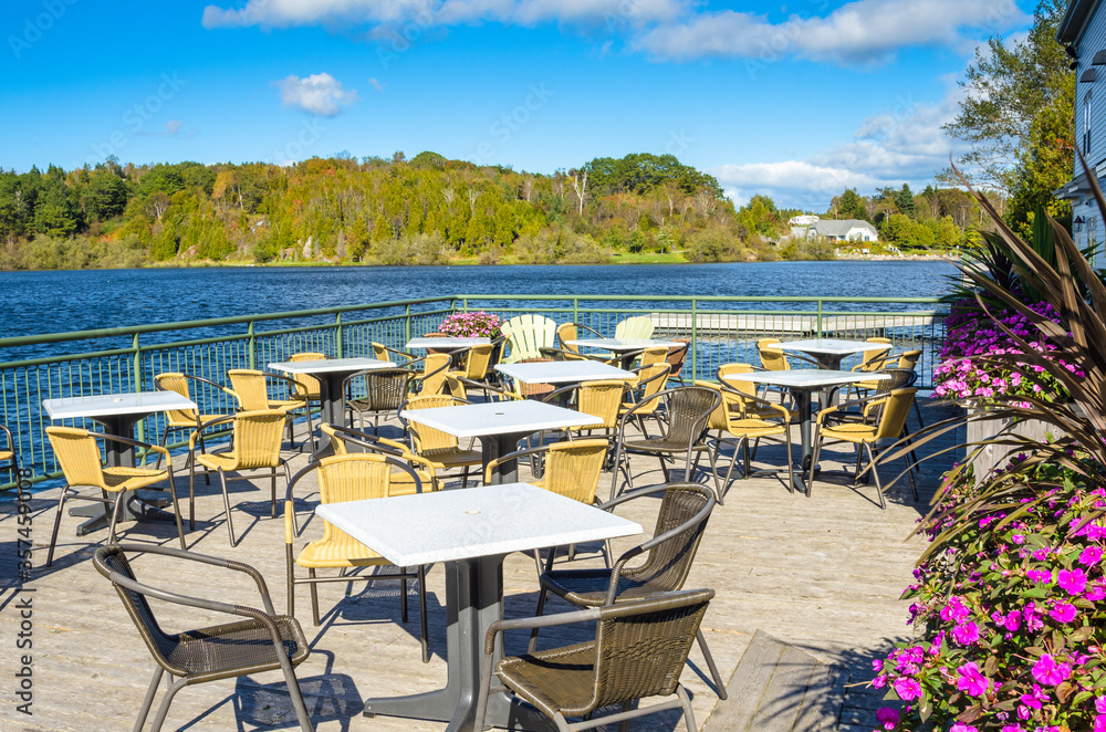 Empty lakeside patio with tables and chairs on a clear autumn day