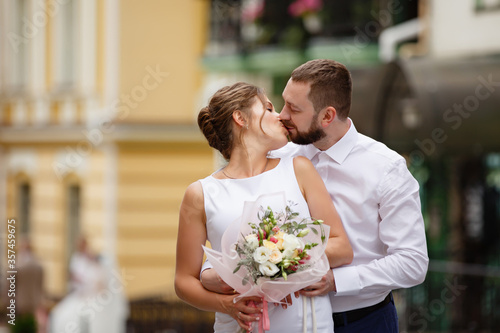 Young Bride and Groom couple in summer old City garden. Tender holding each other. woman and man couple. Romantic walk of young happy family near hydrangea bush. lovers newlyweds street style wedding